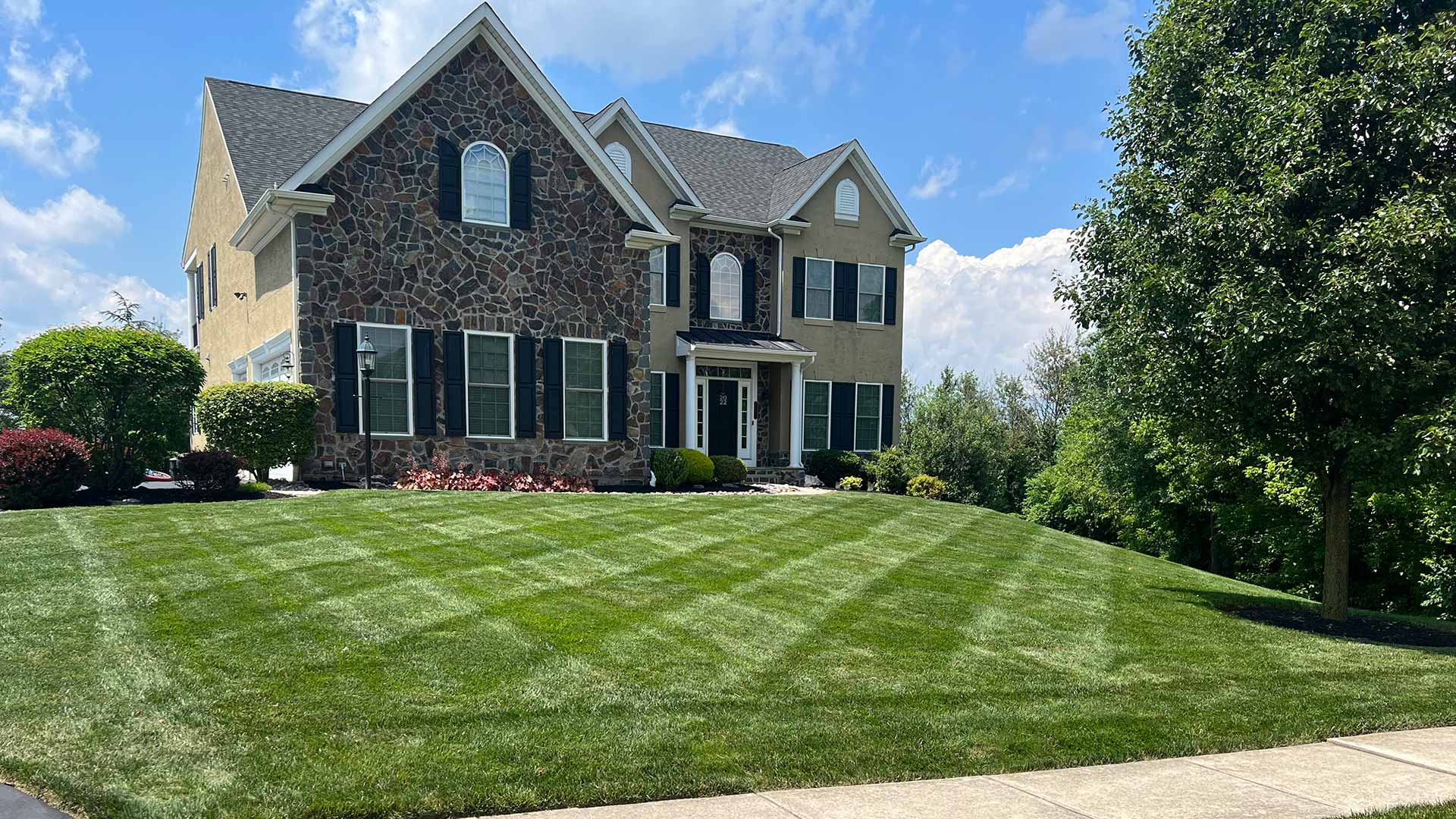Beautiful natural stone home with gorgeous green lawn grass near Lansdale, PA.